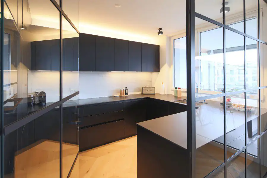 Eine Küche mit schwarzen Schränken und Glastüren, die modern und elegant wirkt.
